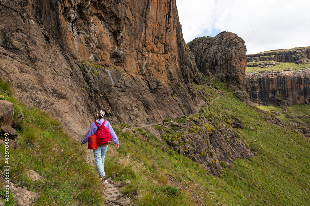 Woman hiking on a path along the rock at Drakensberg mountains