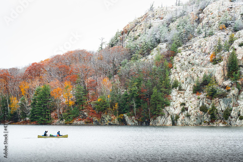 Men Paddling Canoe across Northern Lake with Forest and Snowy Mountain