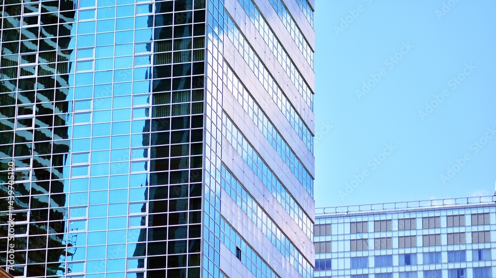 Glass facade of the buildings with a blue sky. Modern building in the business city center. Background of modern glass buildings. Glass facade of the buildings with a blue sky. Modern building in the business city center. Background of modern glass buildings.