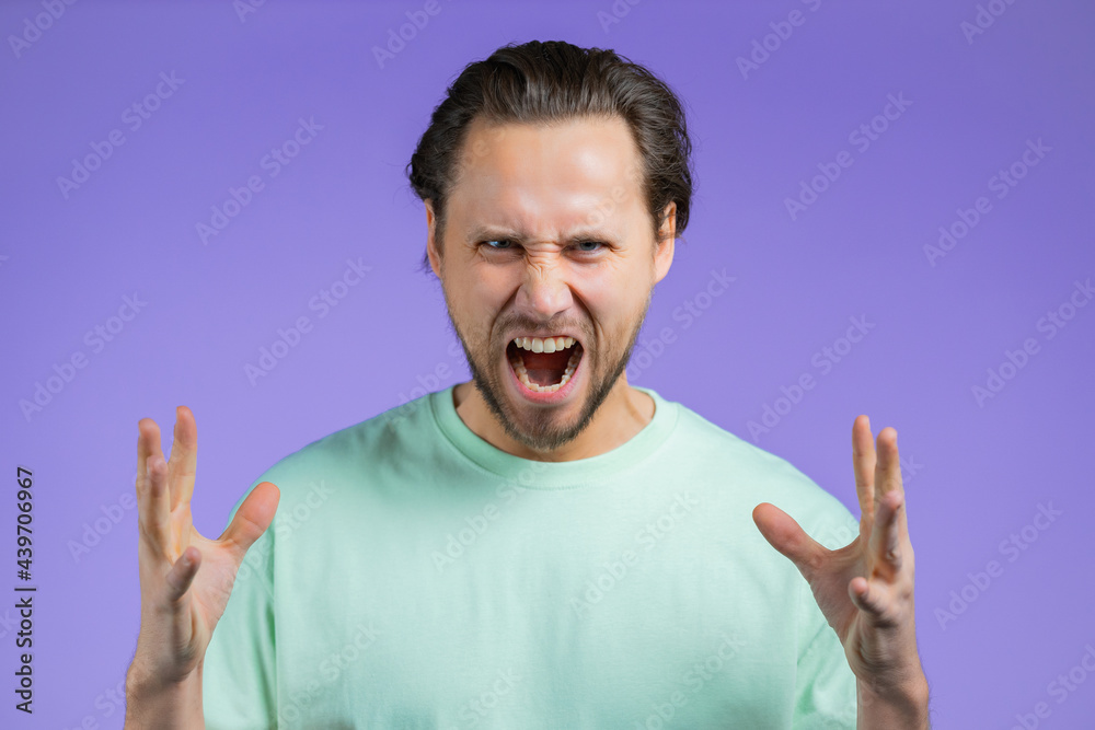 Man in rage on violet background. European guy in stress, he is in aggression and looking at camera with hatred Man in rage on violet background. European guy in stress, he is in aggression and looking at camera with hatred