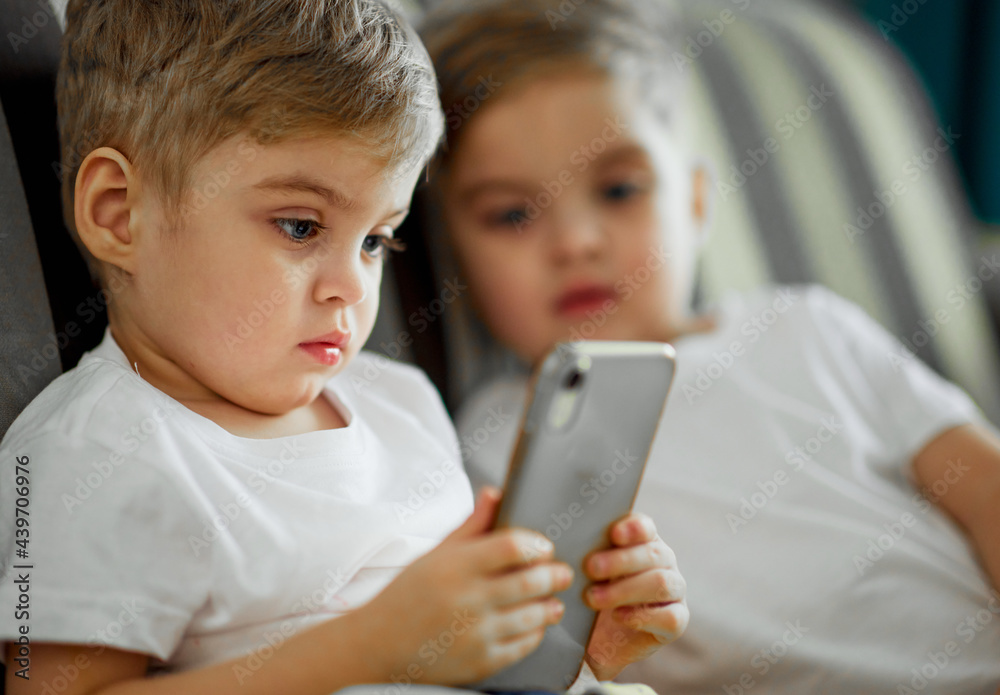 Twin brothers watching video on smartphone Twin brothers watching video on smartphone
