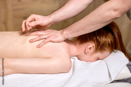 unrecognizable redhead woman getting massage on spine, skin care, spa concept, massage, relax. in modern spa center, body therapy
