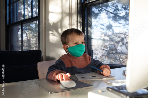 Little boy in face mask using desktop computer photo