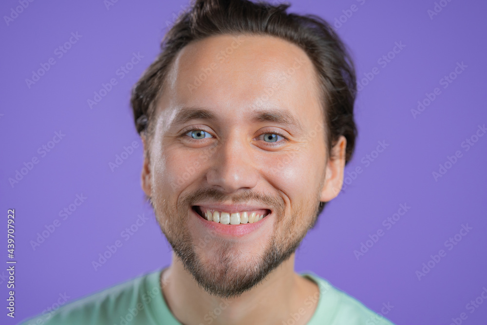 Portrait of smiling european man. Young handsome guy with beard on violet studio background.