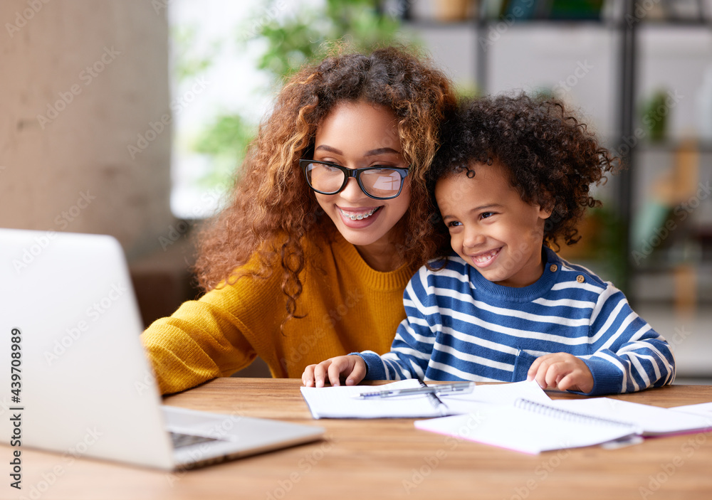 Happy afro american family mom and son watching funny videos on laptop at home Happy afro american family mom and son watching funny videos on laptop at home
