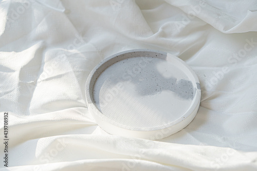 Empty round tray on white textured linen background, designer jewelry plate