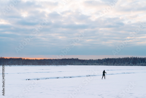Winter landscape with dawn and a skiing man walking in the snow.