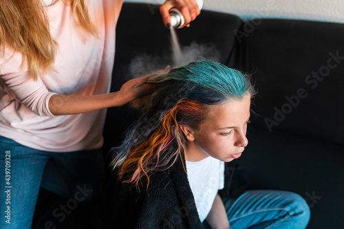 Modern mother painting daughter hair with coloring spray photo