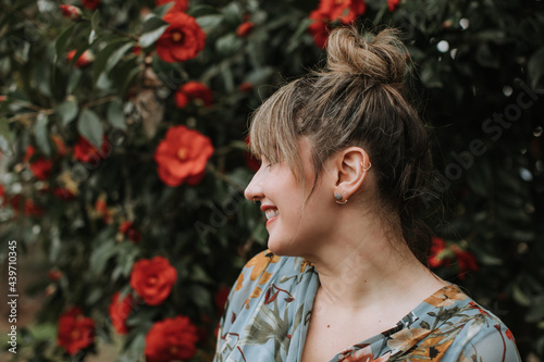 A Smiling Woman with Nose and Ear Piercings Smiles in front of Flowers photo