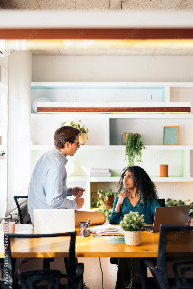 © Santi Nuñez/Stocksy - Coworkers Chatting and Working in Office