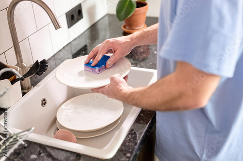 Konstfotografi Unrecognizable male hands washing dishes at kitchen sink while doing cleaning at