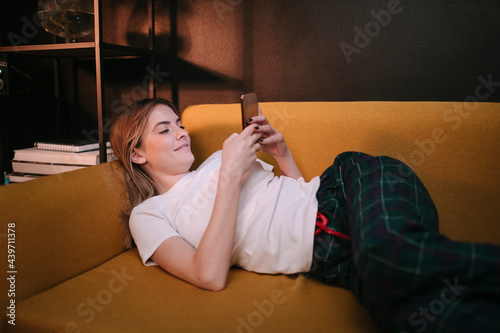 Young Woman Lying On Couch Using Her Cell Phone at home photo