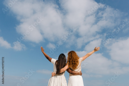 Two women of different nationalities over a blue sky photo