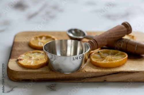 Tranches de citron séchées sur une planche à découper en bois avec une fraction d'une tasse à mesurer en métal avec manche en bois au look rustique avec lumière naturelle photo