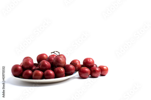 group of plums on a plate with white background