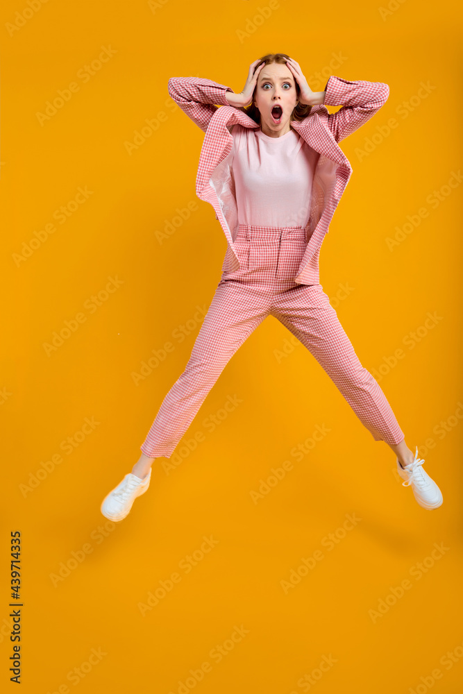 surpsied caucasian lady in suit in shock, emotional woman with red hair jumping omg expression isolated over bright vivid shine vibrant yellow color background surpsied caucasian lady in suit in shock, emotional woman with red hair jumping omg expression isolated over bright vivid shine vibrant yellow color background