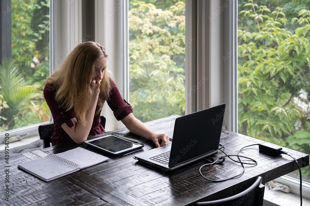 Teenage Girl Learning in Online Class at Home with Laptop Tablet and Paper Notebook Teenage Girl Learning in Online Class at Home with Laptop Tablet and Paper Notebook