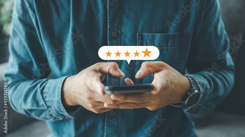 close up Man hand using smartphone with popup five star icon for feedback review satisfaction service, Customer service experience and business satisfaction survey. photo