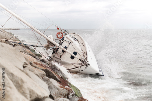 Wrecked sailboat at the coast with waves impact photo