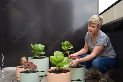 A woman inspects her plant pots on balcony garden