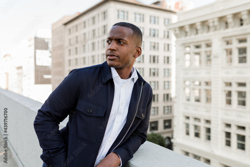 Handsome Businessman Leans Against a Wall on a Rooftop in Downtown Handsome Businessman Leans Against a Wall on a Rooftop in Downtown
