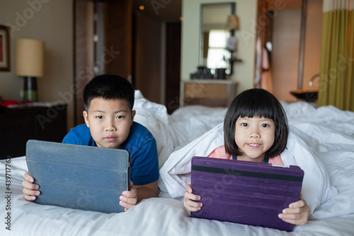 two children addicted tablet, asian kid watching cartoon