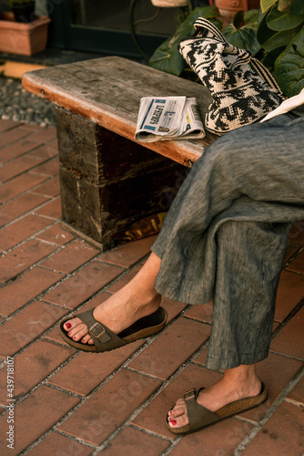 Legs of a woman sitting on a bench with a newspaper photo