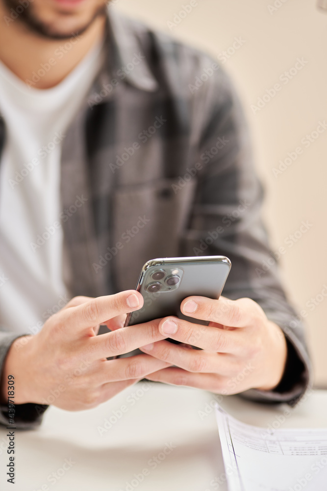 Crop man browsing smartphone in workspace Crop man browsing smartphone in workspace