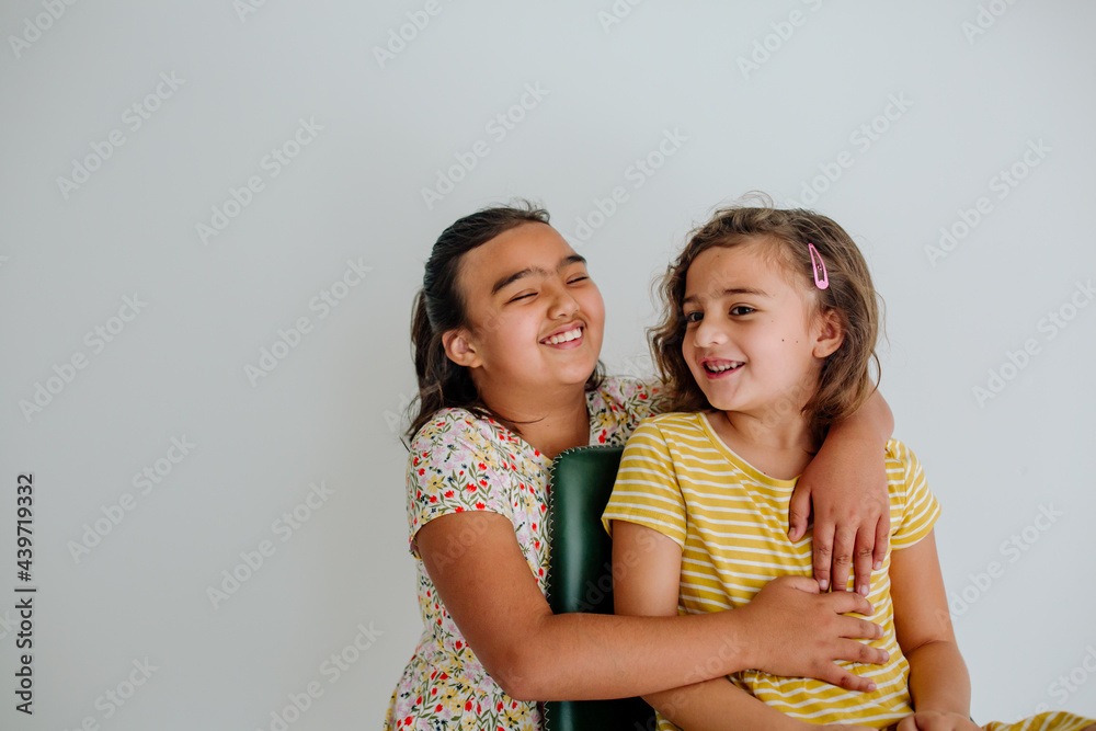 Laughing young biracial sisters in chair Laughing young biracial sisters in chair