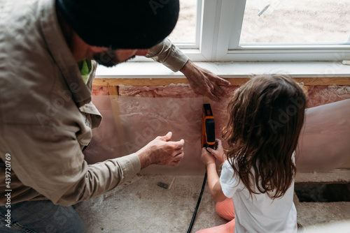 Father teaching daughter how to use a power tool.  photo