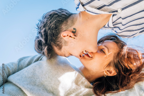 Smiling lesbian women about to kiss against blue sky photo
