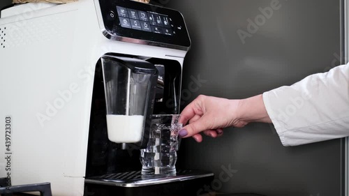 Home coffee machine making hot latte or cappuccino. Steaming milk in the glass. Close-up. Turn on coffee maker. Morning hot drink closeup