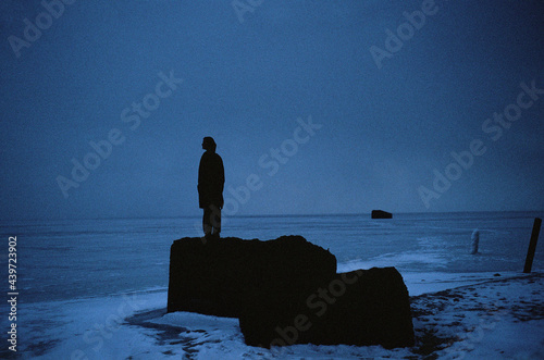 A girl stands on the rocks near the sea