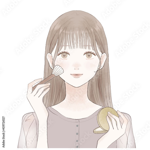 パウダリーファンデーションをメイクブラシで顔に塗る女性