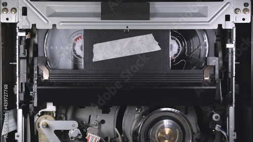 Video cassette inserting in VCR, playing from beginning of tape, then at the end of tape player ejects VHS, copyspace
