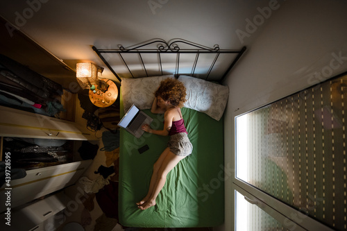 Young woman on bed naviating throght internet photo