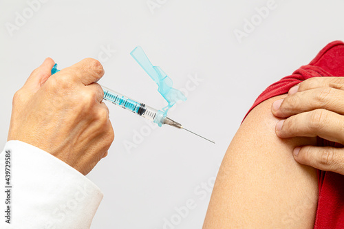mão segurando uma seringa com a agulha apontada para o braço do paciente pronta para receber a dose da vacina photo
