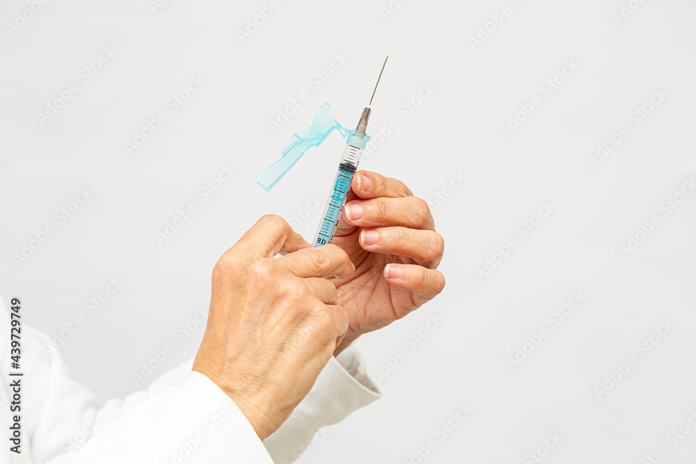 detalhe das duas mãos da enfermeira segurando uma seringa, verificando a dose do medicamento detalhe das duas mãos da enfermeira segurando uma seringa, verificando a dose do medicamento