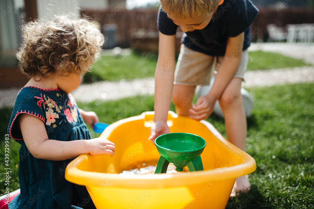 close up siblings playing with water outdoors on a summers day close up siblings playing with water outdoors on a summers day
