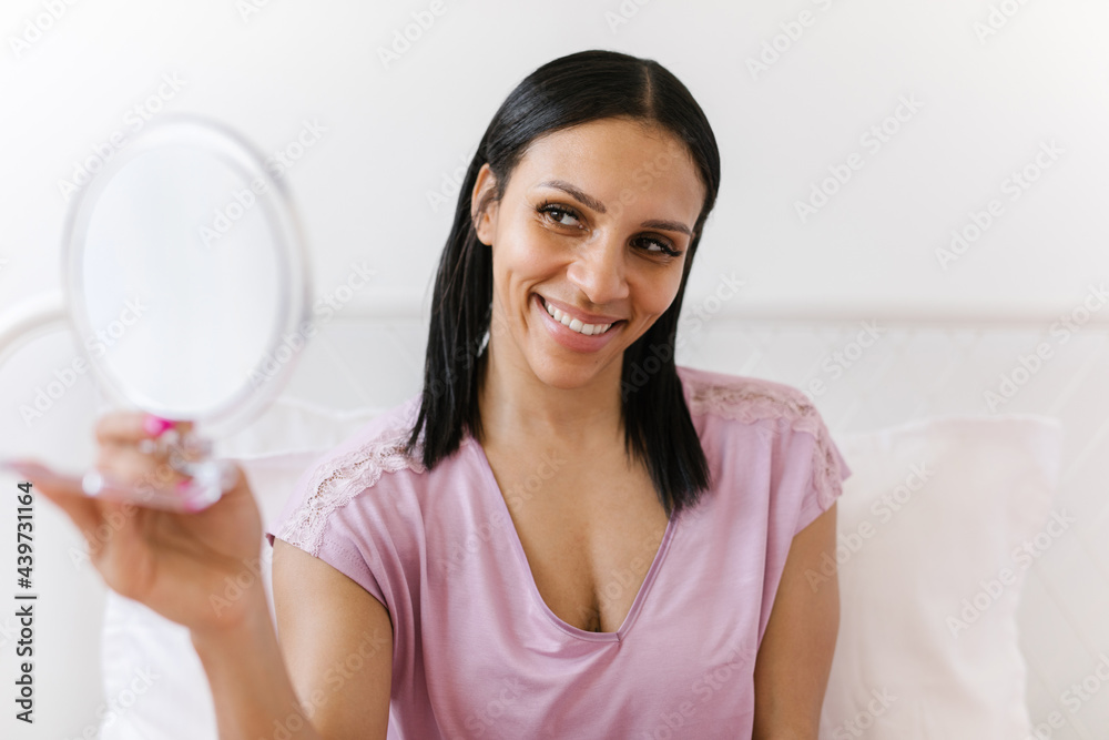 Beautiful black woman applying facial lotion while looking in the mirror Beautiful black woman applying facial lotion while looking in the mirror