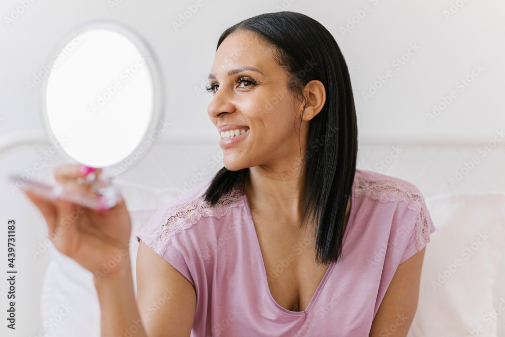 Beautiful black woman applying facial lotion while looking in the mirror Beautiful black woman applying facial lotion while looking in the mirror