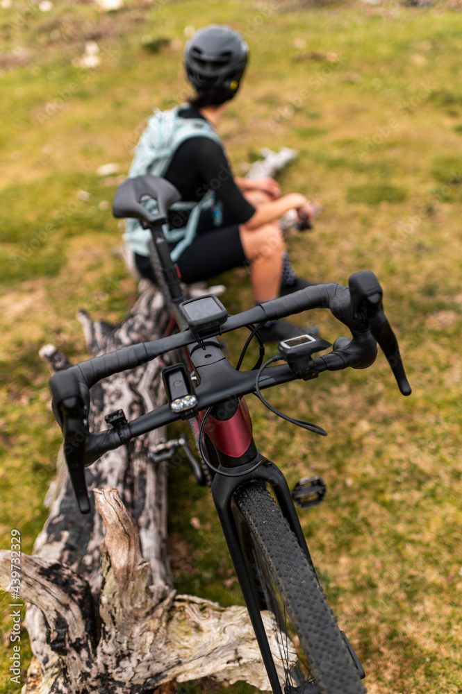 Mountain biker resting seated in tree trunk near electric bike Mountain biker resting seated in tree trunk near electric bike