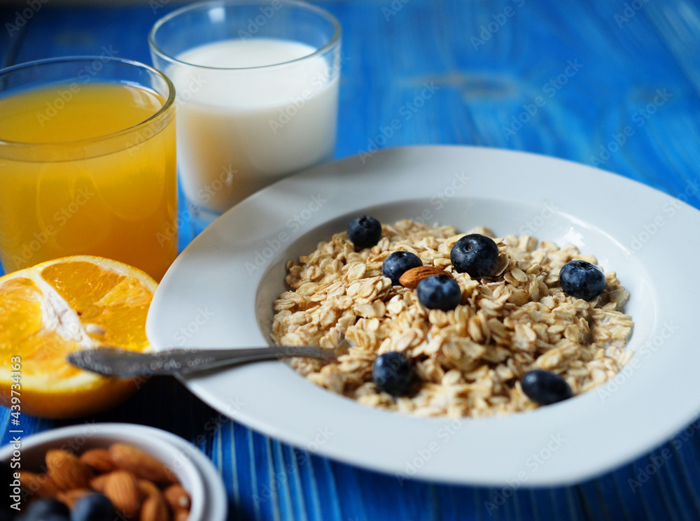 oatmeal with fresh berries on white plate with orange juice and milk, oatmeal with fresh berries on white plate with orange juice and milk,