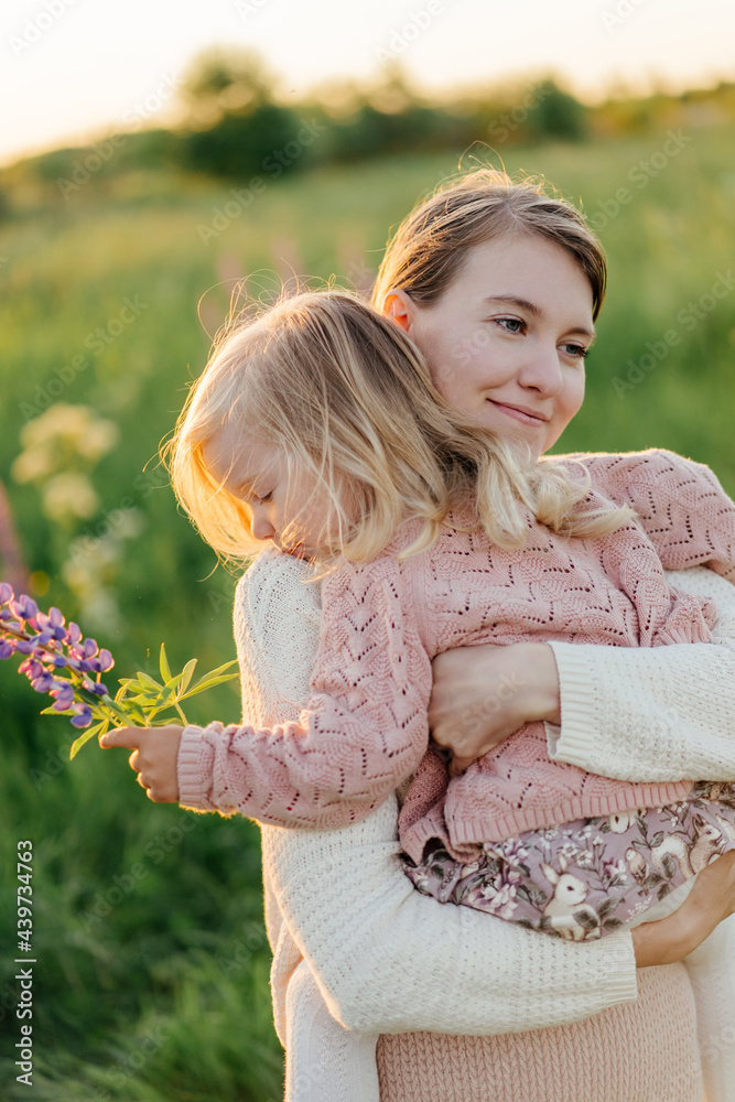 Cheerful mother embracing daughter in field in evening Cheerful mother embracing daughter in field in evening