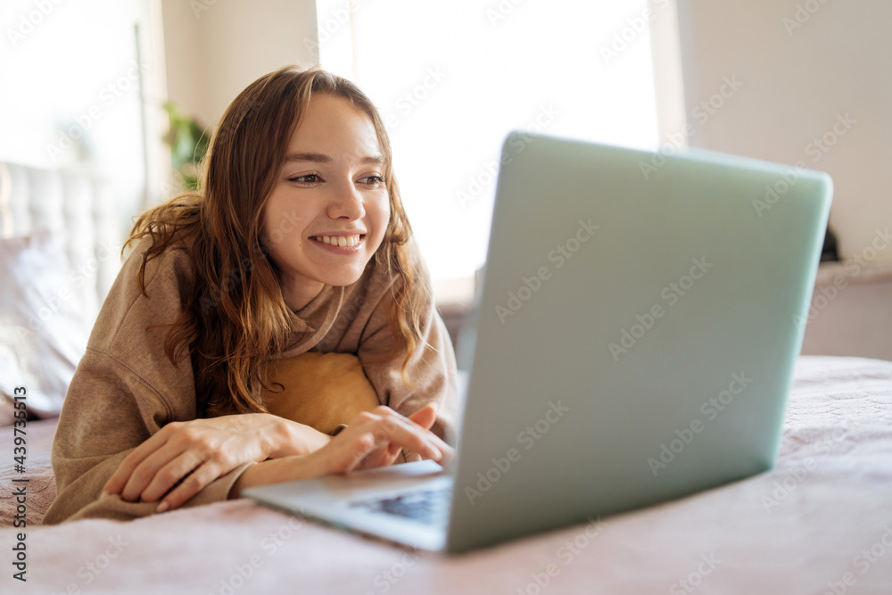 young woman makes a video call while lying in bed young woman makes a video call while lying in bed