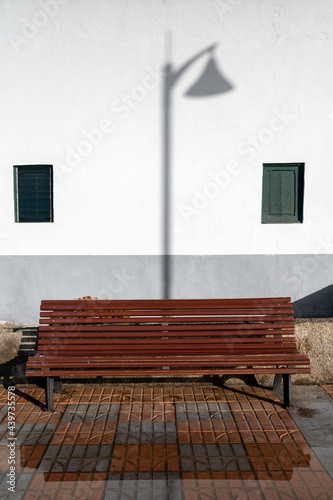 The shadow of a lamppost and a bench. photo