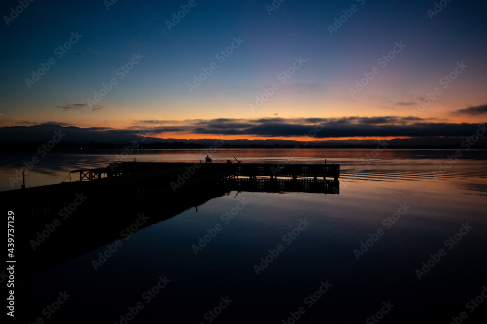 Obraz premium blue sunrise on the wooden pier by the lake