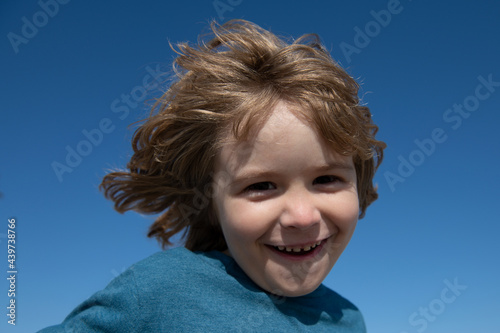 Portrait of a happy laughing child on blue sky with copy space. Close up positive kids face. © Volodymyr