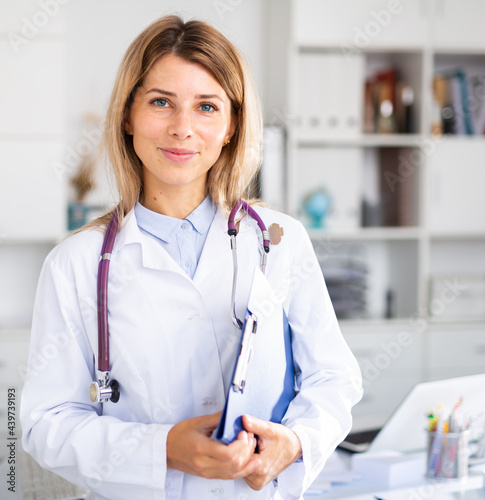 positive female doctor with stethoscope working in cabinet photo