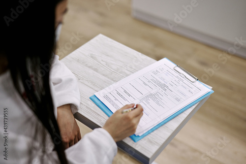 Doctor writing anamnesis about patient in blank  photo